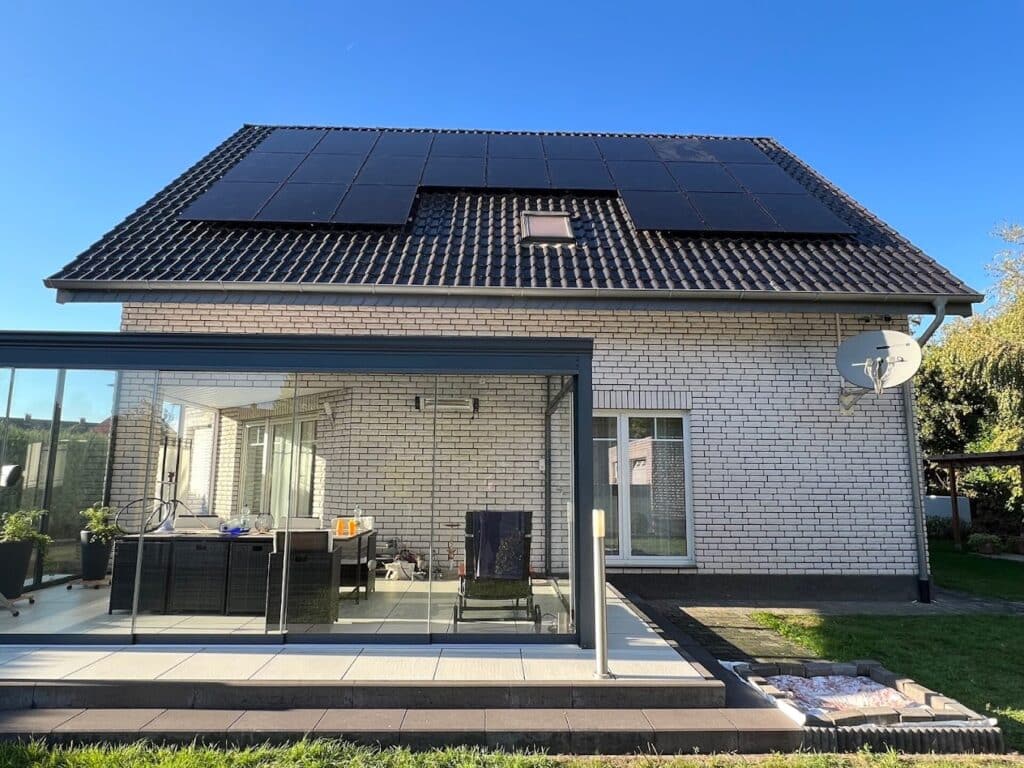Aufnahme von Vorne eines Hauses mit Photovoltaikmodulen auf dem Dach